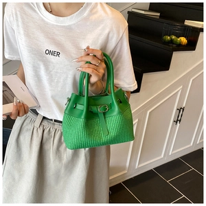 Detailed view of the emerald green woven bucket bag with smooth leather patchwork and buckle