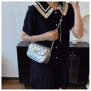 Detail of silver quilted crossbody bag with metal chain strap and turn-lock closure