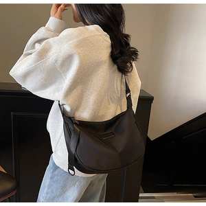 Detail view of black nylon crescent bag featuring adjustable strap and buckle on model