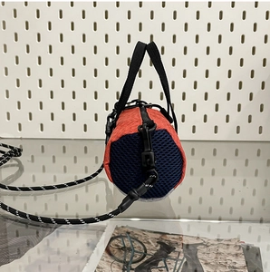 Detailed close-up of orange woven cylinder bag with navy mesh and woven strap
