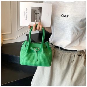 Detail of emerald green bucket bag featuring a woven texture and leather contrast
