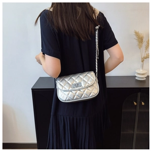 Detail showing the silver quilted chain bag with a metallic finish and twist-lock clasp
