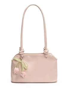 Pink faux leather underarm bag with knot strap and tulip charm on white background