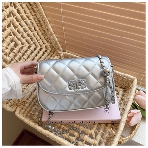 Detail of silver quilted flap crossbody bag with metal chain in a lifestyle setting