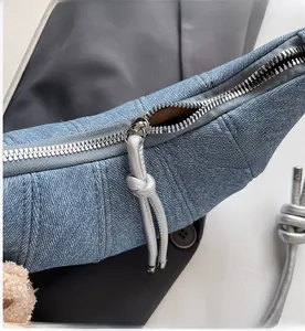 Detail einer hellblauen Denim-Tasche mit silbernem Metallreißverschluss und Knotenzug