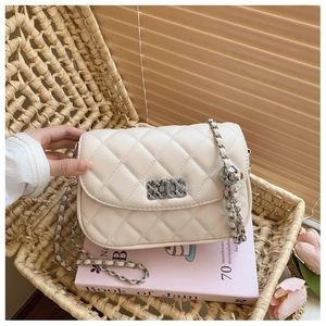 Close-up of off-white quilted chain bag with silver woven lock on a pink book