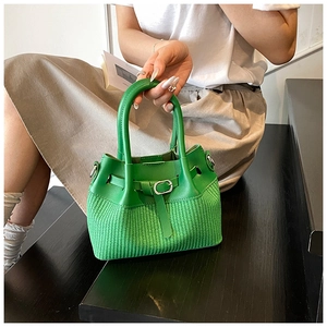 Macro detail of green leather bucket bag featuring woven texture and silver buckle