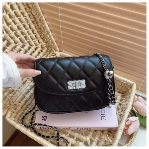 Detail of black quilted crossbody bag with silver chain strap and metal turn lock