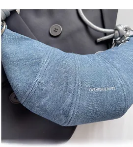 Nahaufnahme der hellblauen Denim-Croissant-Tasche mit Ziernähten und Silberringen