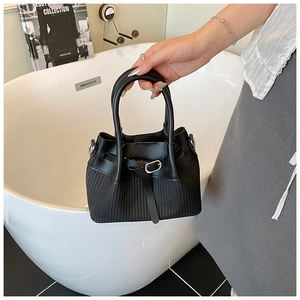 Detailed view of black bucket bag featuring smooth leather and woven texture stitching