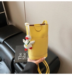 Detail of yellow lychee pattern leather mini crossbody bag with a cute duck charm