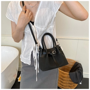 Close-up of black bucket bag featuring woven texture detail and silver buckle accents