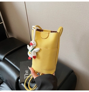 Detail van gele leren mini crossbodytas met een schattige witte eendenhanger eraan