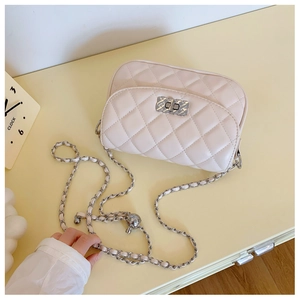 Close-up of cream quilted chain bag with silver twist lock and metal decorative ball