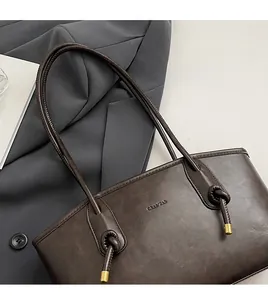 Dettaglio di una borsa tote in pelle marrone con spalline sottili e minuterie metalliche dorate