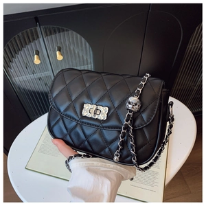 Detailed view of black quilted crossbody bag with luxury chain strap and silver buckle