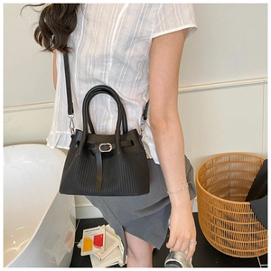 Detail of black bucket bag featuring textured vertical stripes and silver buckle accents