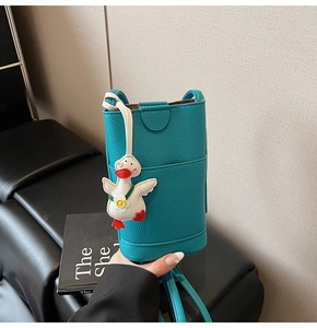 Detail of green pebble leather mini bucket bag with a cute white duck charm accessory