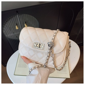 Detail of beige quilted leather mini bag with silver chain strap and metal twist lock
