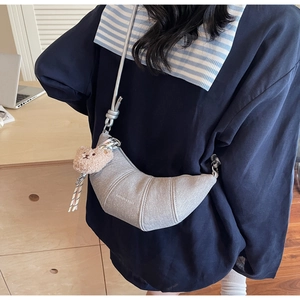 Detail der grauen Croissant-Tasche mit Denim-Textur und süßem braunem Plüschbär