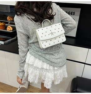 Fashionable white quilted leather crossbody bag with star charm worn by a model