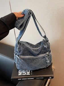 Large denim crossbody bag in acid wash blue with multiple zipper pockets and wide strap