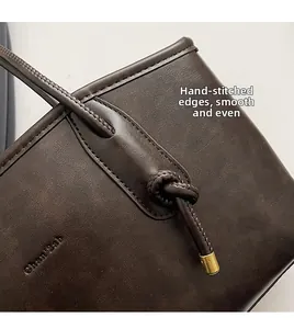 Dettaglio della borsa tote in pelle marrone scuro con cuciture a mano e finiture dorate