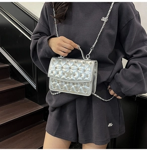 Detail of silver quilted chain bag featuring a star buckle and rhinestone rivets