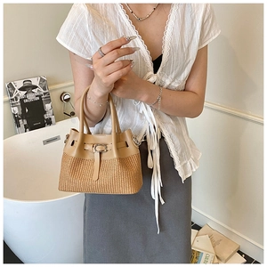 Detail of beige leather and straw woven bucket bag with fine strap metal buckle detail