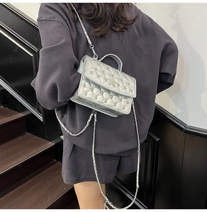 Detail of silver quilted handbag with rhinestone star and metallic chain strap on a model