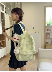 Detail view of light green plaid backpack with a zipper pocket and plush rabbit charm