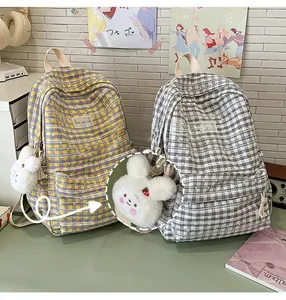 Detail view of plaid school backpacks in yellow-blue and grey-white with plush bunny charms