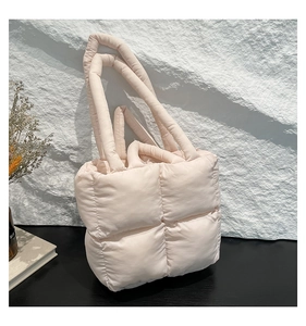 Detail der hellbeigen gesteppten Puffer-Tasche mit gepolsterten Griffen auf modernem Grund