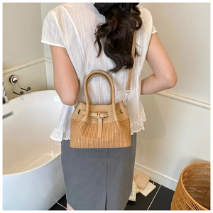 Detail of camel leather and woven straw bucket bag with round handles and adjustable strap