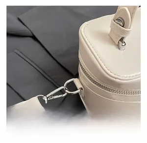 Détail du crochet en métal argenté et de la fermeture éclair sur sac blanc crème