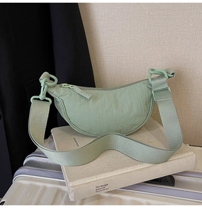 Detail of mint green nylon crescent bag with wide strap and matte texture hardware