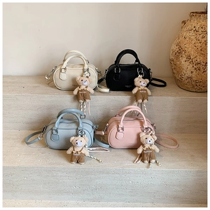 Close-up of four colors of litchi texture mini Boston bags with bear charms on stone steps