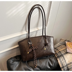 Dettaglio borsa tote in pelle sintetica marrone scuro con spalline sottili e ciondolo a racchetta