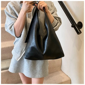 Practical large-capacity black leather tote bag worn by a model on a shoulder