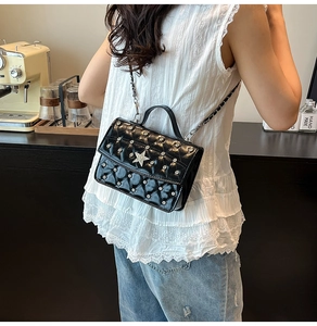 Close-up of black quilted patent leather bag with silver star and rhinestone detailing