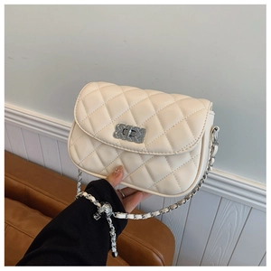Detailed close-up of quilted beige crossbody bag with silver chain strap and metallic lock