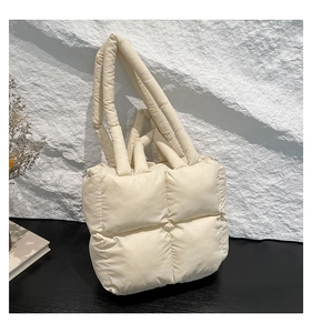 Detailansicht der cremefarbenen gesteppten Puffer-Tasche mit glänzendem Finish