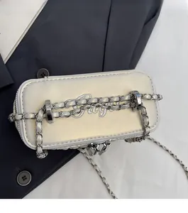 Detailed shot of pearl white quilted handbag with silver chain and artistic embroidery