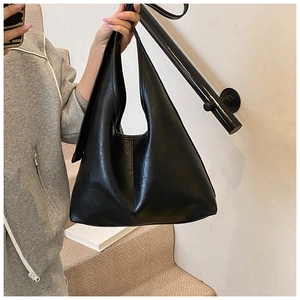 Detail of minimalist black hobo bag showing natural wrinkled faux leather texture