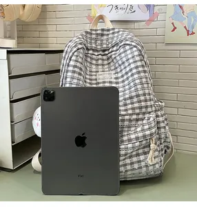 Size comparison of a grey plaid backpack next to an iPad showing storage capacity