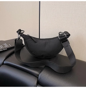 Detail of a minimalist black nylon crescent bag with adjustable wide shoulder strap
