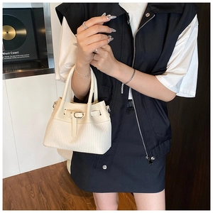 Close-up of cream white bucket bag featuring woven textures and metal buckle hardware