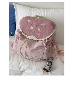 Close-up of pink guava themed backpack with seed embroidery and a penguin charm