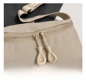 Detail view of smooth dual zippers and durable shoulder strap stitching on beige canvas bag