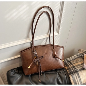 Dettaglio borsa shopper marrone scuro con ciondolo a treccia e texture in ecopelle fine